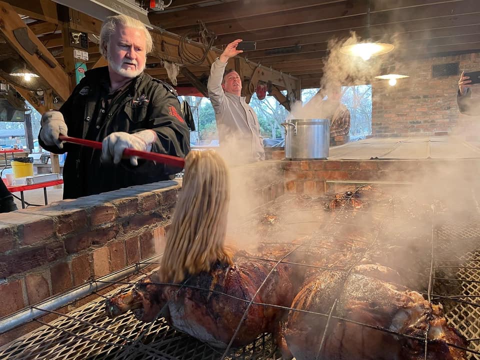 Myron Mixon working the coals over a whole hog on the open masonry pit